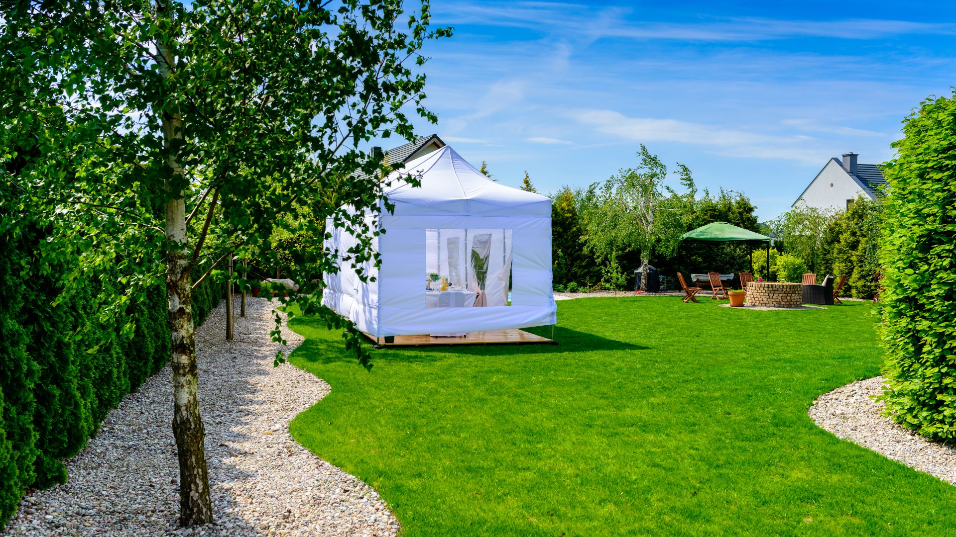Moderner weißer Pavillon im gepflegten Privatgarten mit Rasenflaeche und Baumallee