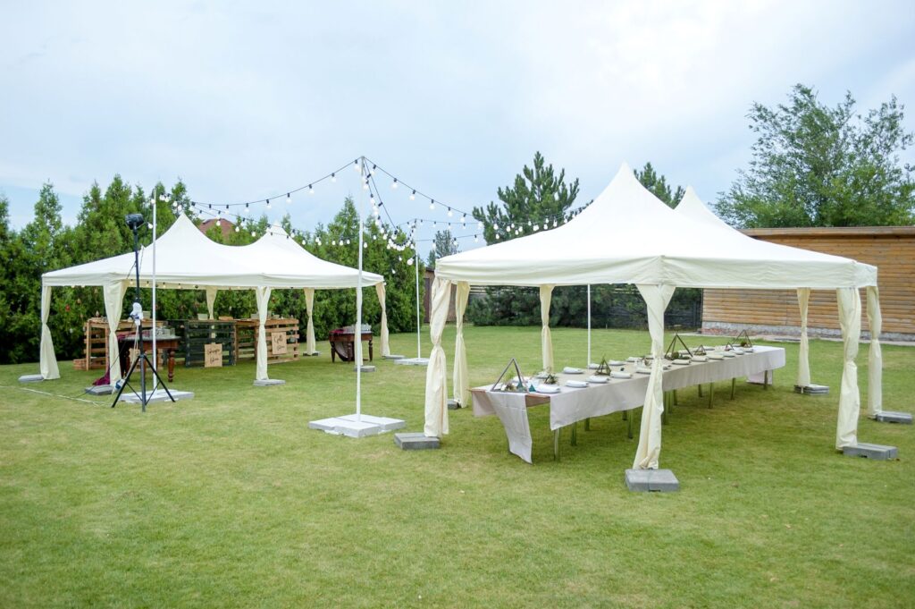 Mehrere Pavillons mit Buffet und Lichterkette fuer eine festliche Gartenfeier